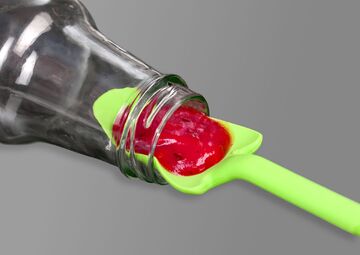 Der hellgrüne Löffel holt rote Marmelade aus einem dünnen Flaschenhals.