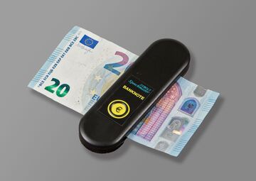 Ansicht auf den schwarzen Geldscheinprüfer, in welchem gerade ein 20-Euro-Schein steckt. 