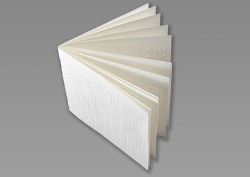 Ansicht auf ein aufgeklapptes Braille-Buch in Weiß.