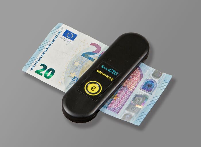 Ansicht auf den schwarzen Geldscheinprüfer, in welchem gerade ein 20-Euro-Schein steckt. 