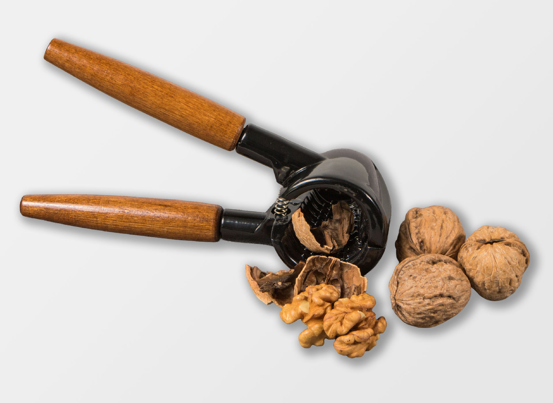 Ansicht auf den Nussknacker mit Holzgriff und schwarzem Werkzeug mit Walnüssen.