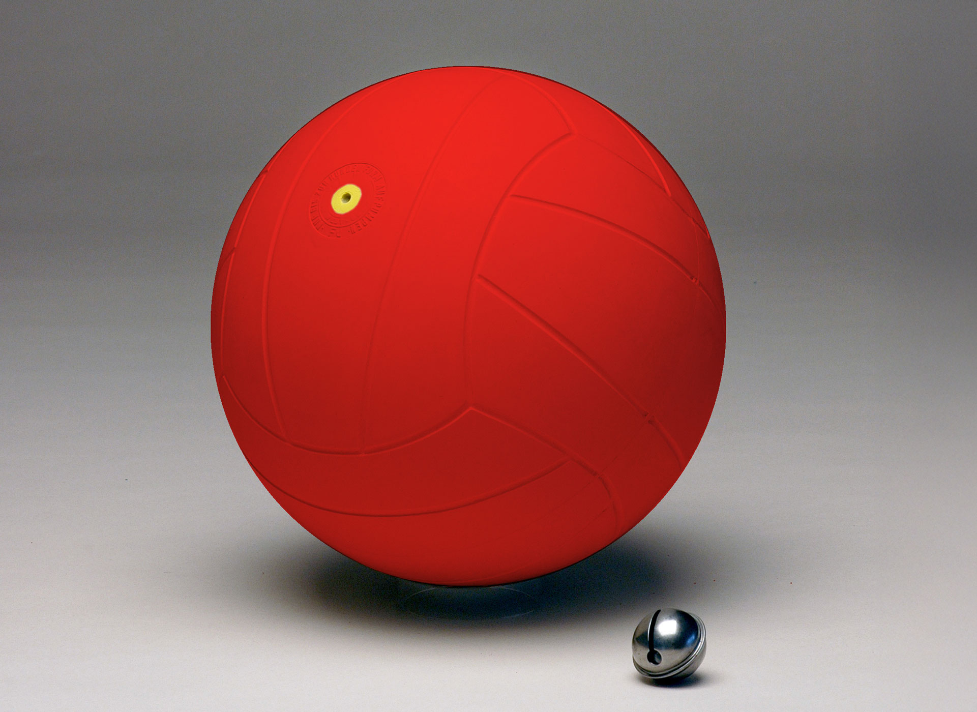 Ansicht auf den roten Ball. Davor liegt eine kleine silberne Rassel.